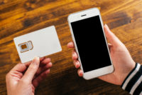 Woman holding smartphone and new SIM card
